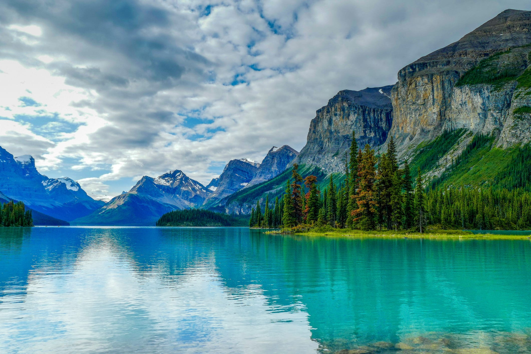 The picturesque Spirit Island is a world famous Canadian Rockies landmark on Maligne Lake, Jasper National Park, Alberta, Canada. In the background is part of the Hall of the Gods, with Mount Warren, Valad Peak, Mount Henry MacLeod, Coronet Glacier and Mount Mary Vaux visible.