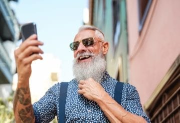 Bearded senior using mobile phone outdoors