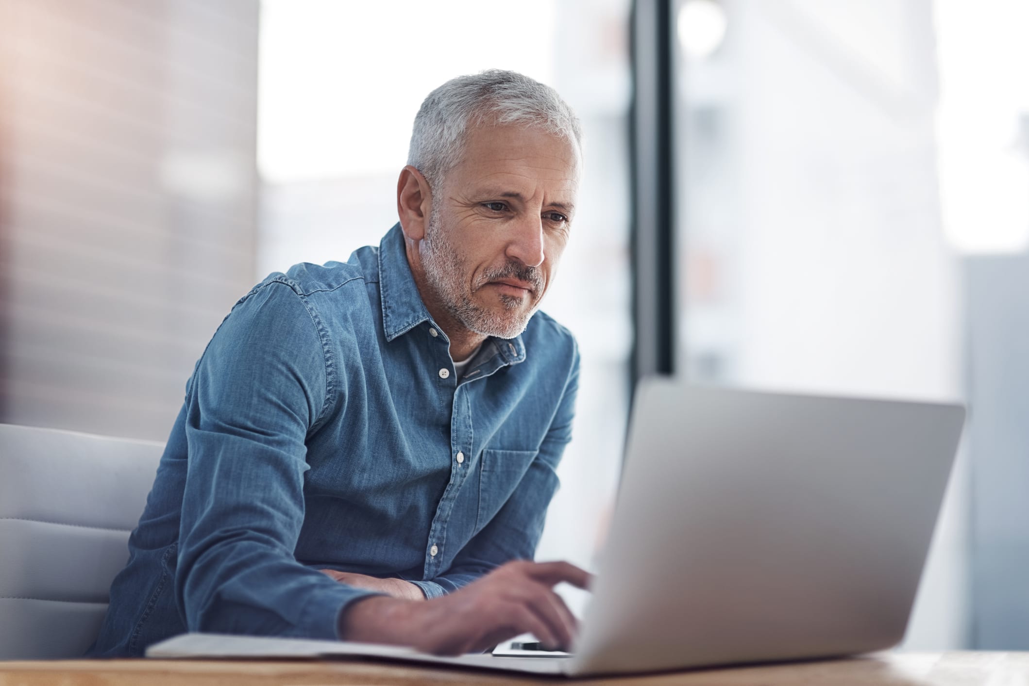 Cropped shot of a mature businessman working on a laptop in an office