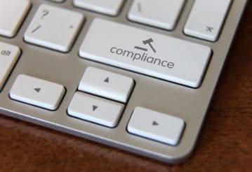 Close up of a keyboard, but instead of a shift key, there is a compliance key