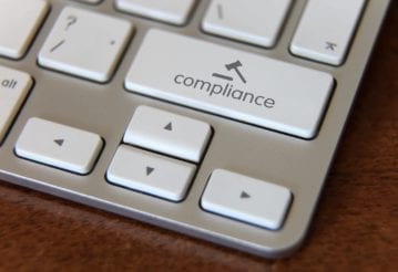 Close up of a keyboard, but instead of a shift key, there is a compliance key