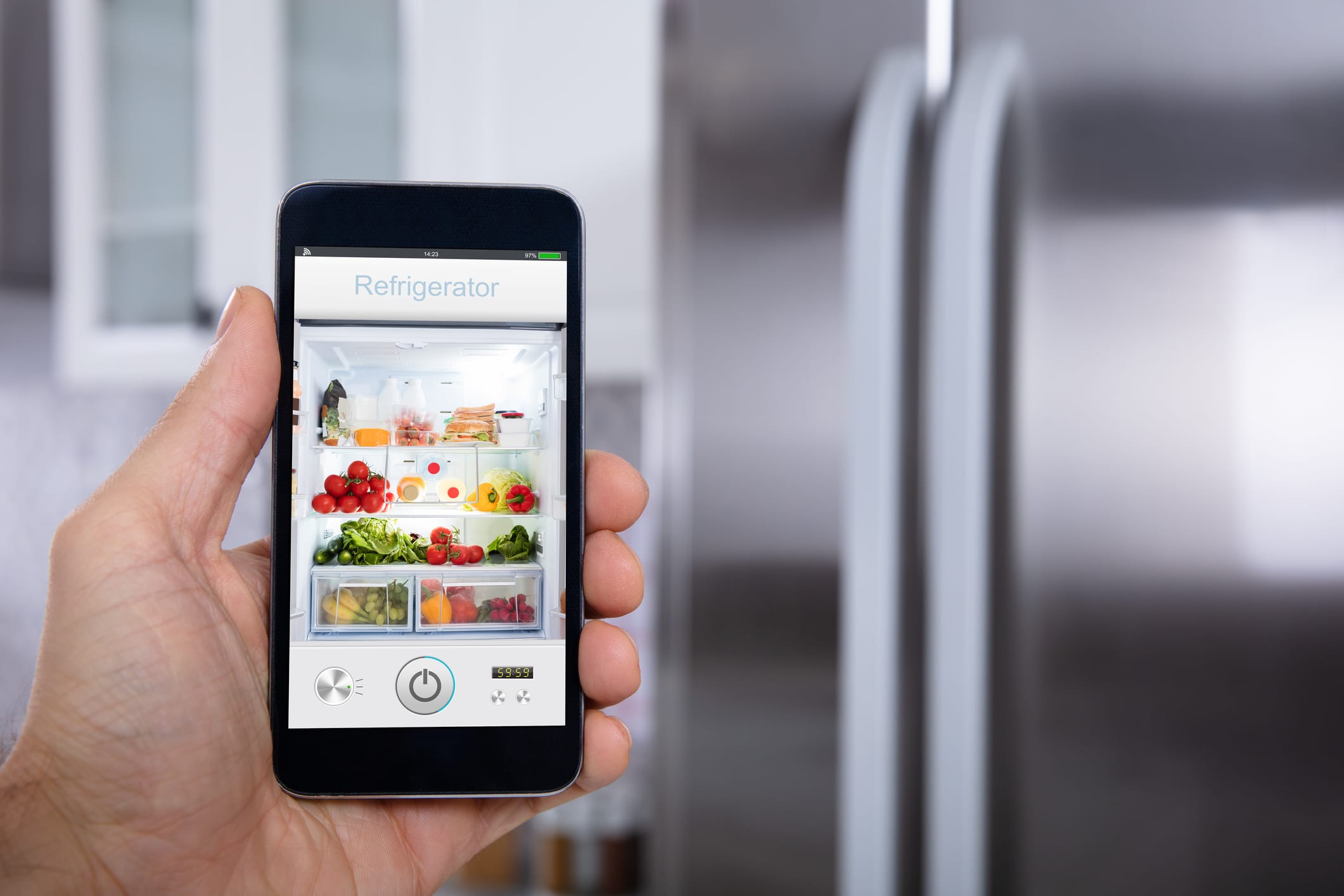 Close-up Of A Person's Hand Operating Refrigerator With Mobile Phone