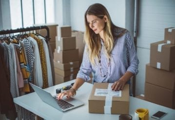 Female owner of a small business packing her product in boxes, and preparing it for delivery.