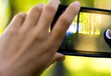 Using a mobile phone to take a photo of a forest