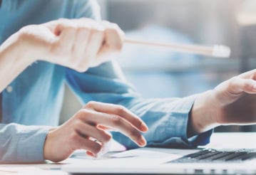 Two people working and pointing at a laptop.