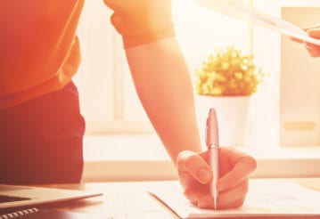 A woman's hand write on a notepad on a table