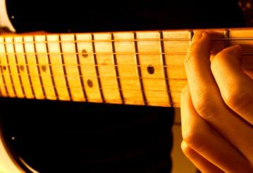 Close up of hands playing an electric guitar