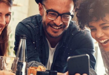 Laughing friends crowded around a mobile phone