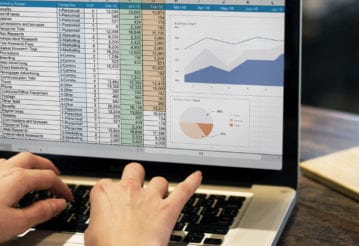 Woman typing on a laptop that has excel open