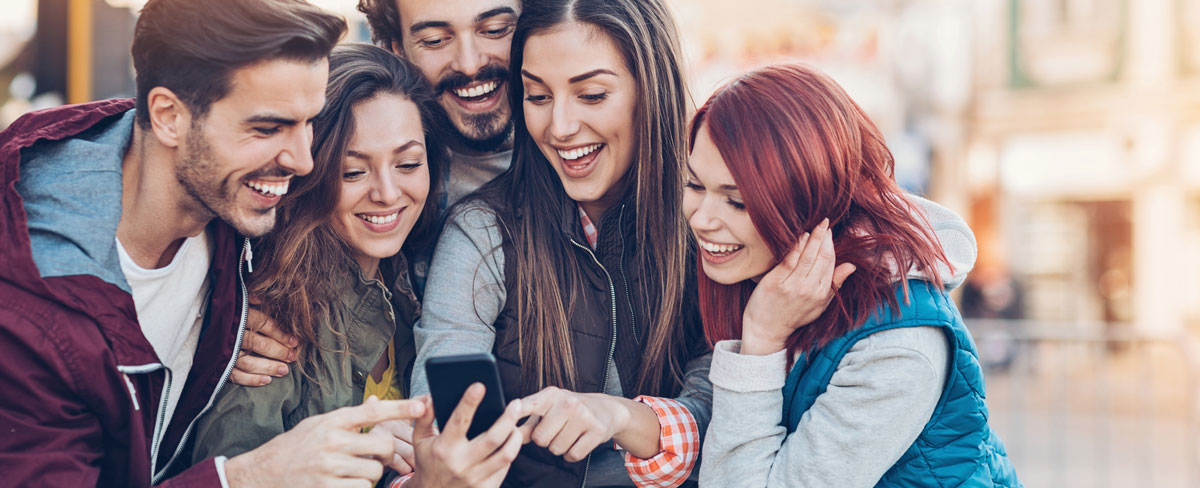 Group of friends looking at a smart phone outdoors in the city