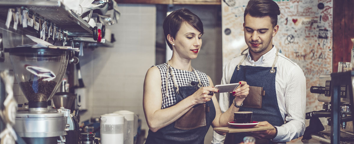 Two restaurant workers take mobile photo of latte