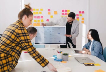 group of office workers at conference table. Post-its cover the wall in behind them