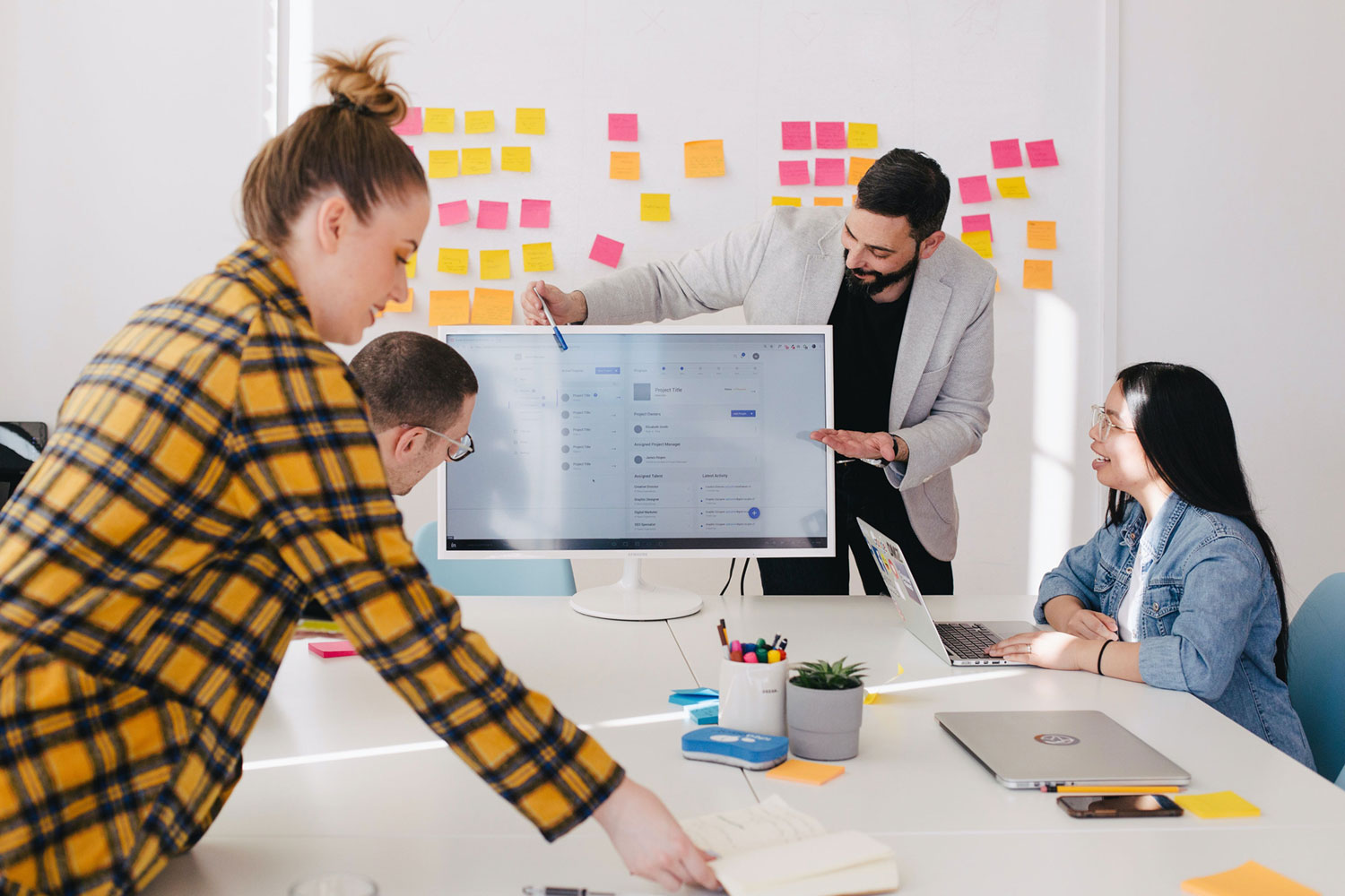 group of office workers at conference table. Post-its cover the wall in behind them