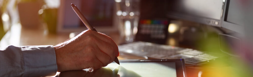 Hand holding a stylus draws on a digital drawing tablet