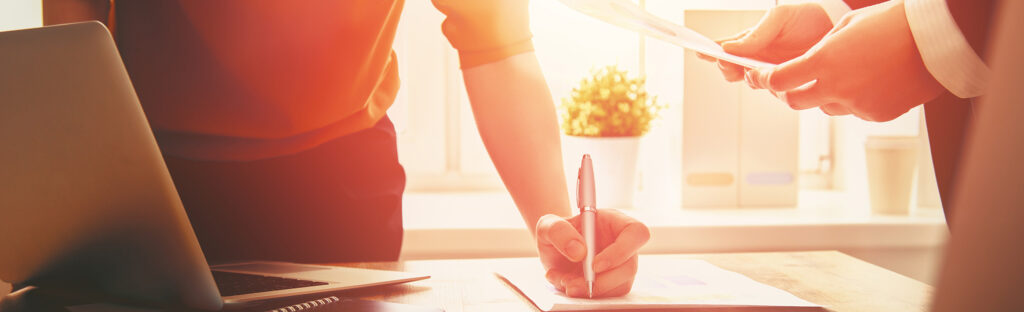 A woman's hand write on a notepad on a table