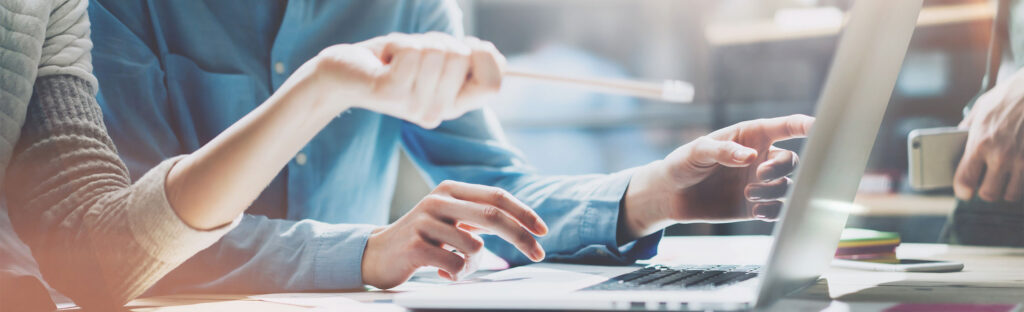 Two people working and pointing at a laptop.