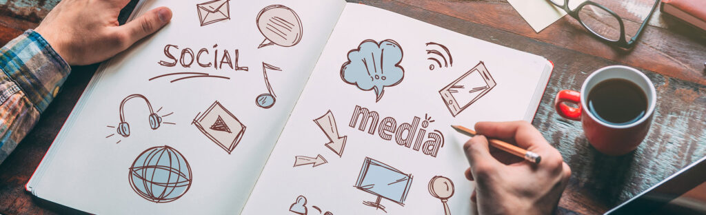 An open sketch book on a table with social media related illustrations.