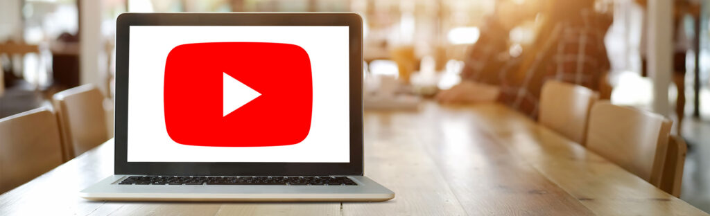Laptop on a long table with the YouTube logo on its screen