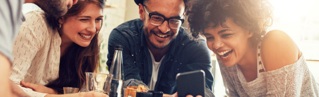 Laughing friends crowded around a mobile phone
