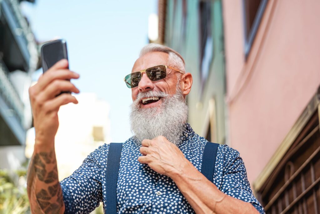 Bearded senior using mobile phone outdoors